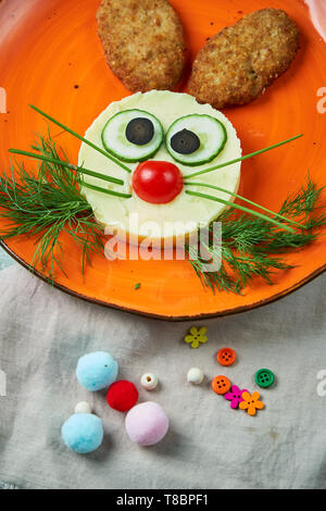 Kids menu, cutlets with mashed potatoes in the form of a hare's head on an orange plate on a gray background Stock Photo