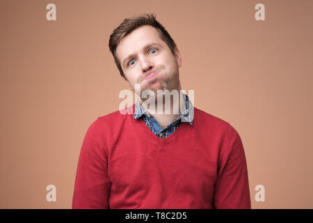 man in red sweater puffing his cheeks, feeling fed up as heis tired. Stock Photo