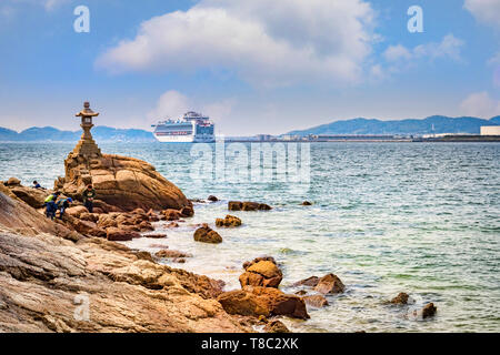 27 March 2019: Gamagori, Japan - The shore of the island of Takeshima, off Gamagori, with the cruise ship 'Diamond Princess' docked in the distance. Stock Photo