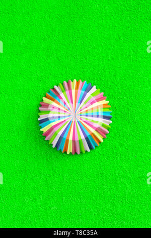 Rainbow colored paper baking cups for muffins and cupcakes on a green background minimal creative concept. Space for copy. Stock Photo
