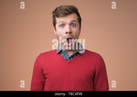 Shocked face of caucasian man in red sweater. Stock Photo