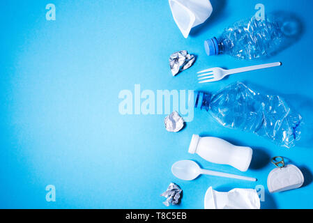 Plastic trash on blue background, eco concept image with copy space. Stock Photo