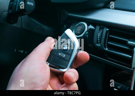 Sankt-Petersburg, Russia, November 16, 2017: BMW X5 F15 start car key in a male hand near start/stop push button. Modern car interior details. The key Stock Photo