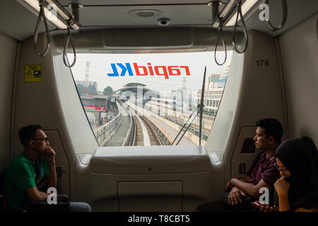 Passengers looking through window of driverless commuter train as it drives into Rrailway station, elevated tracks and station, Kuala Lumpur, Malaysia Stock Photo