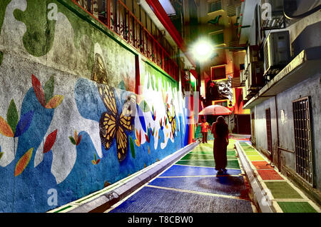 People walking past colorful mural in residential alley, Kuala Lumpur, Malaysia Stock Photo