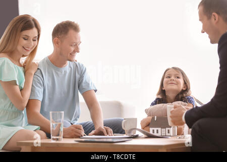 Husband signing a contract for buying house in office of estate agent Stock Photo
