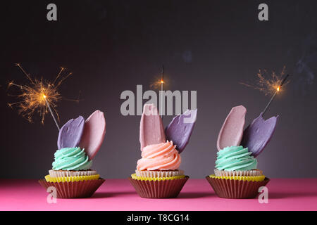 Delicious birthday cupcakes with sparklers on table against dark background Stock Photo