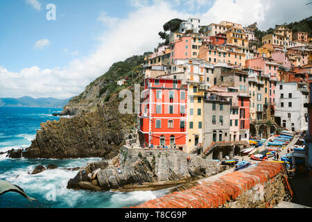 Classic view of beautiful Riomaggiore, one of the five famous picturesque fisherman villages of Cinque Terre, on a sunny day with blue sky and clouds  Stock Photo