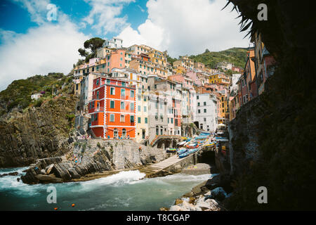 Classic view of beautiful Riomaggiore, one of the five famous picturesque fisherman villages of Cinque Terre, on a sunny day with blue sky and clouds  Stock Photo