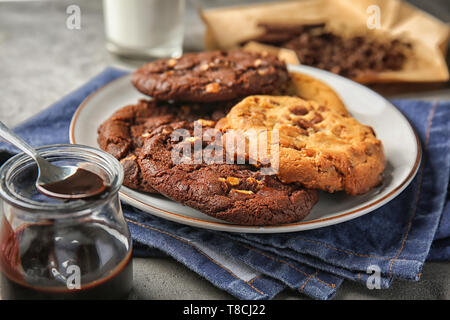 Plate with tasty cookies and melted chocolate on table Stock Photo
