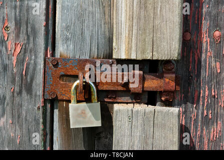 An old rusty padlock on wooden barn door Stock Photo