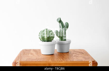 Ceramic cacti in pots on table against white background Stock Photo