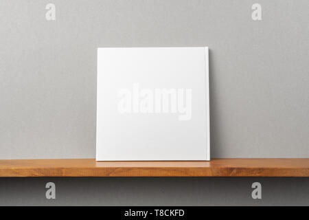 Design concept - back view of square white notebook on bookshelf and grey wall for mockup Stock Photo
