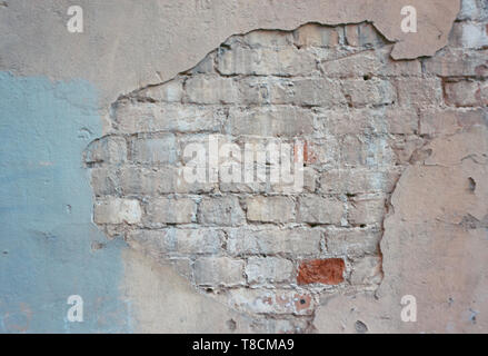 Abandoned old brick wall of the building with painted and crumbling cladding Stock Photo
