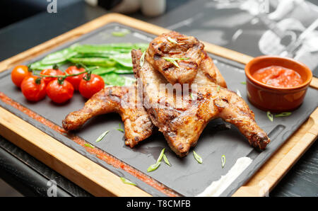 Grilled chicken with tomatoes and sauce on stone plate, British food Stock Photo