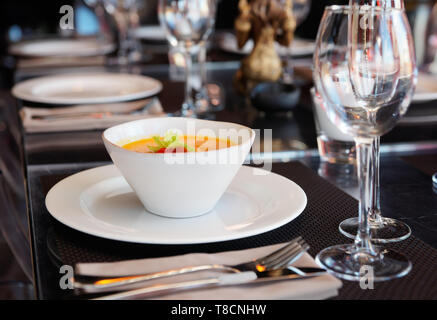 Dish with pumpkin soup on set restaurant table Stock Photo