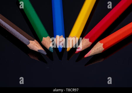 the tips of coloured wooden pencils on a black background with mirror image Stock Photo