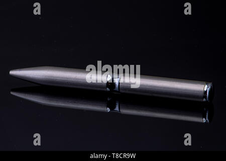silver ballpoint pen on black reflective background Stock Photo