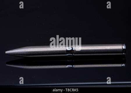 silver ballpoint pen on black reflective background Stock Photo