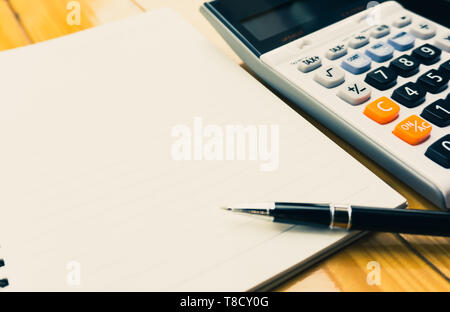 Business planning, finance and various taxes concepts. Blank notebook, black pen and calculator on wooden table with copy space. Depicts a the prepara Stock Photo