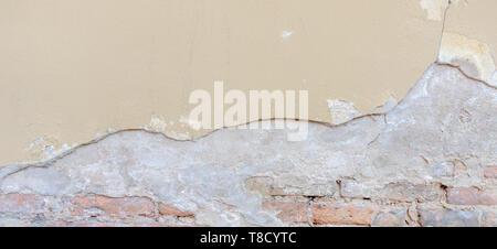 Old grungy red brick wall with peeled beige stucco background. Vintage retro plaster wall with dirty cracked scratched texture background Stock Photo