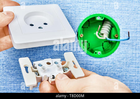 Electrician is connecting two parts of new european standard socket with round green electrical box, electrical work. Stock Photo