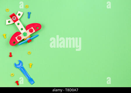 Toy wooden plane, bolts and toys tools on green background Stock Photo