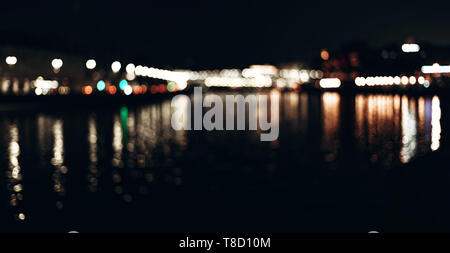 Abstract background of colorful blurred city lights with bokeh effect reflected on water. Stock Photo