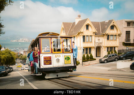 SEPTEMBER 3, 2016 - SAN FRANCISCO: Powell-Hyde cable car climbing up steep hill in central San Francisco with famous Alcatraz Island in the background Stock Photo