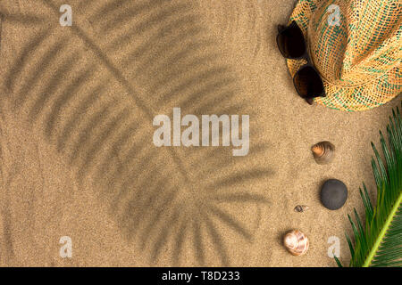 Stylish summer composition with green leaves, hat and sunglasses on a sand background with shadows. Artwork mockup with copy space Stock Photo