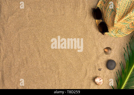 Stylish summer composition with green leaves, hat and sunglasses on a sand background. Artwork mockup with copy space Stock Photo