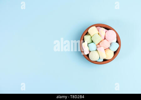 Marshmallows in a round bowl, isolated on blue background. Top view. Stock Photo