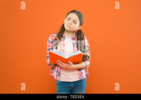 Study language. Child doing homework writing in workbook. Girl hold book and pen. Girl cute write down idea notes. Notes to remember. Write essay or notes. Exercising writing workbook. Making notes. Stock Photo