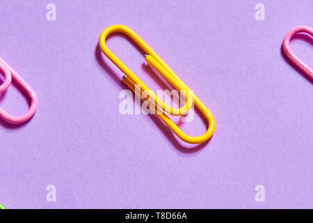 yellow paper clip between pink ones, close up photo. connection element Stock Photo