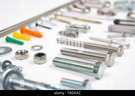 An assortment of carpenters material like screws, bolts, fixings, nuts screws and nails on a white background. Stock Photo