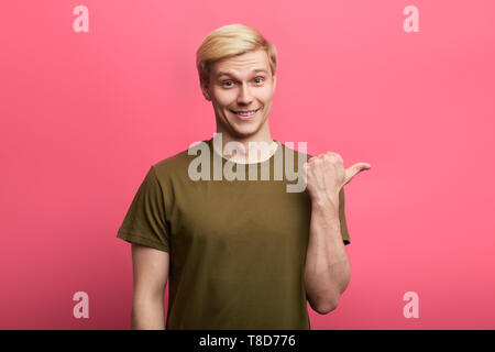happy good looking man looking at the camera and pointing to the side with thumb up.copy space. place for text. choise Stock Photo