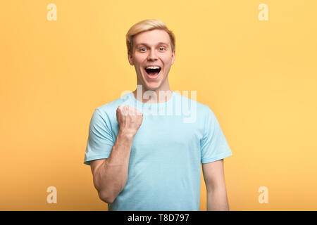 positive gorgeous young emotional man raising clenched fists in hooray gesture, rejoicing at his success. lick, happiness concepts , winner celebrating his victory Stock Photo