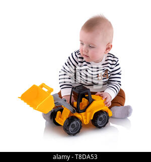 Pretty baby boy plays with toy, isolated on white background with shadow reflection.  Adorable small boy playing with plastic yellow excavator toy. To Stock Photo