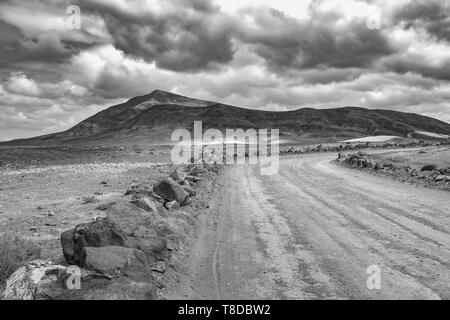 on the road to Papagayo beach with view to the volcanic mountain Hacha Grande on a cloudy day, black and white picture Stock Photo