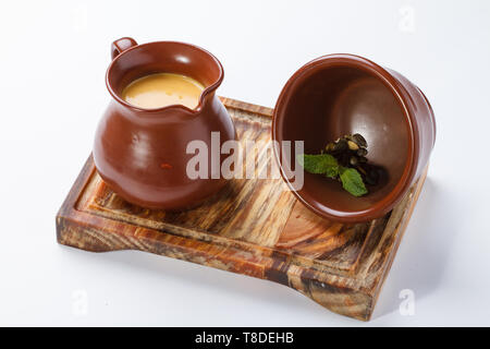 Pumpkin soup served in a Clay Jar/pot served on a wooden board, isolated on white. Stock Photo