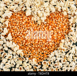Heart made of delicious popcorn and kernels on table Stock Photo