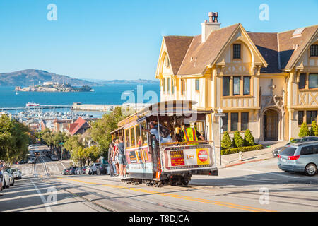 SAN FRANCISCO, USA - SEPTEMBER 25, 2016: Powell-Hyde cable car climbing up steep hill in central San Francisco with famous Alcatraz Island in the back Stock Photo