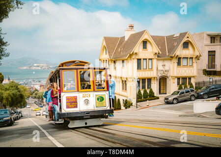 SAN FRANCISCO, USA - SEPTEMBER 3, 2016: Powell-Hyde cable car climbing up steep hill in central San Francisco with famous Alcatraz Island in the backg Stock Photo