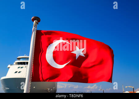Red National Flag of Turkey with a half month and a star against the sky and a ocean liner, Turkish state symbol, autumn, spring, summer Stock Photo