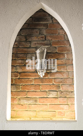 Medieval metal glove, detail of part of ancient armor, detail of war. Shining iron glove against the brick wall background Stock Photo