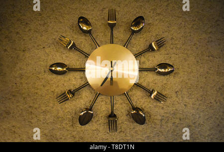 Metallic shining watch especially made for restaurants decoration with forks, spoons and knifes Stock Photo