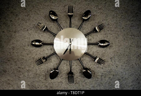 Metallic shining watch especially made for restaurants decoration with forks, spoons and knifes Stock Photo