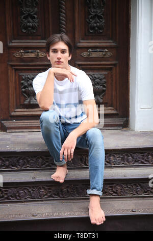 Handsome young man sitting on stairs outdoors Stock Photo