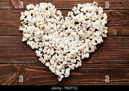 Heart made of delicious popcorn on wooden table Stock Photo