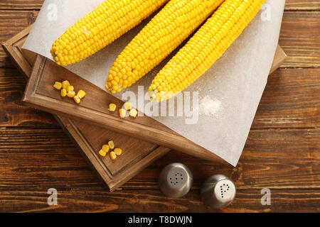 Board with tasty corn cobs on wooden table Stock Photo